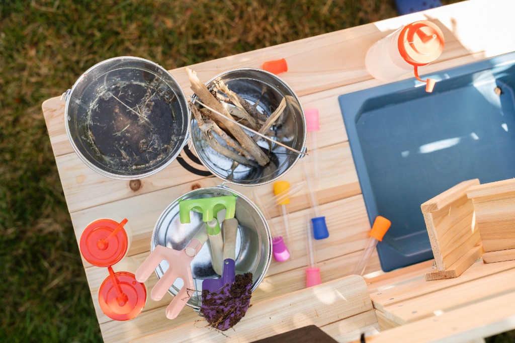 Mud kitchen play station with buckets, dirt, and droppers
